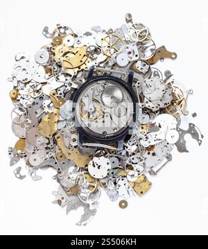 watchmaker workshop - top view of open mechanical watch on heap of old clock spare parts on white background Stock Photo