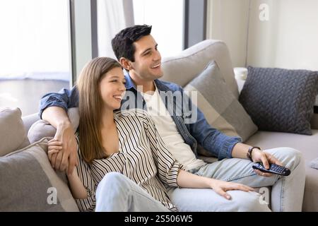 Positive attractive young couple watching romantic movie on TV Stock Photo