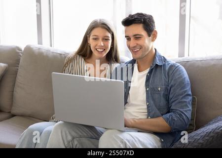 Happy young Latin couple using modern Internet technology at home Stock Photo
