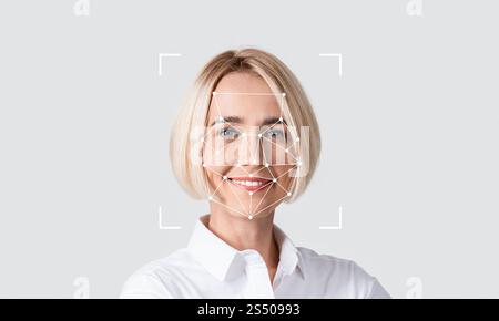 A woman smiles confidently while demonstrating facial recognition technology Stock Photo