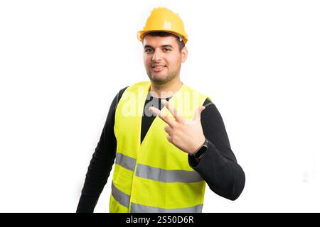 Smiling male builder showing number three with fingers as counting concept wearing helmet and fluorescent vest isolated on white background Stock Photo