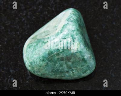 macro shooting of natural mineral rock specimen - polished green Jadeite gemstone on dark granite background Stock Photo