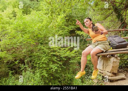Woman using smartphone for pathfinding in forest Stock Photo