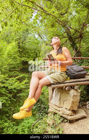 Woman using smartphone for pathfinding in forest Stock Photo