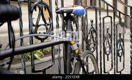 Closeup photo of vintage bicycle locked to metal fence on street. Closeup image of vintage bicycle locked to metal fence on street Stock Photo