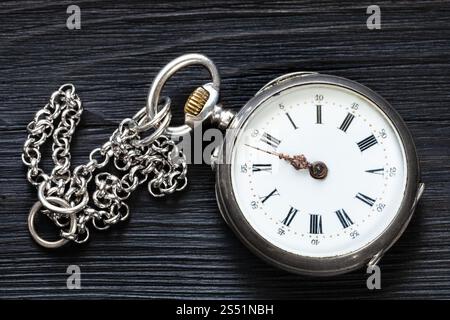 two minutes to twelve oclock on old pocket watch with chain on black wooden background Stock Photo