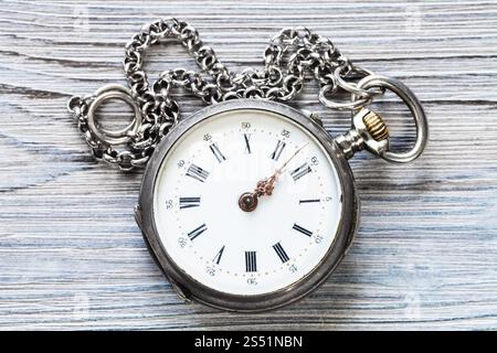 two minutes to twelve oclock on old pocket watch with chain on gray wooden background Stock Photo