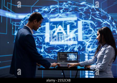 Engineer and coworker use AI cognitive computing to extract information from complex data on laptop. IT staff members using artificial intelligence on notebook to accelerate complex calculations Stock Photo