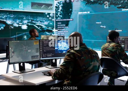 Military specialist in a high tech control center managing satellite radar surveillance, collecting intelligence on cctv computer systems. Interpreting real time data to ensure national defense. Stock Photo