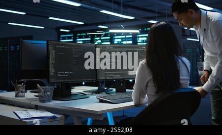 Team of programmers in data center responsible for installation and repair of networking equipment solving tasks. Teamworking colleagues doing maintenance on server room infrastructure, camera B Stock Photo