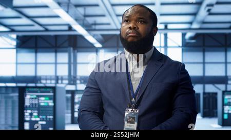 IT expert managing data center with advanced technology, ensuring cybersecurity and efficient network management. Admin in server room maintaining and optimizing data center infrastructure, camera A Stock Photo