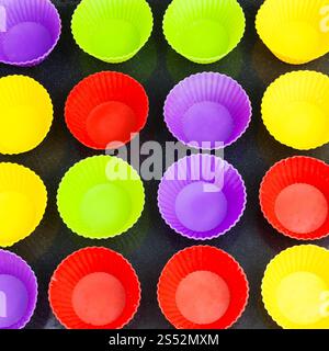 top view of many empty multicolor silicone molds for cupcakes on baking tray Stock Photo