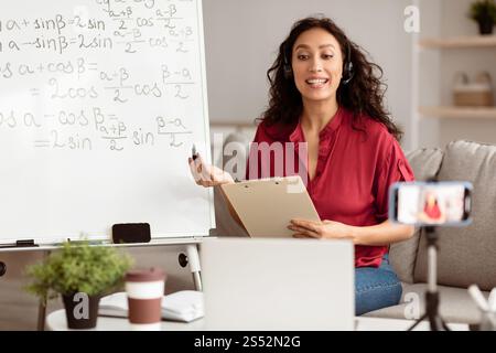 Lady teacher in headset explaining trigonometric functions to students online Stock Photo