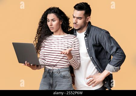 Portrait Of Confused Middle Eastern Couple Suffering Problems With Laptop Stock Photo
