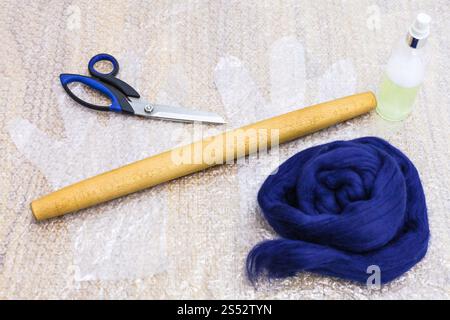 workshop of hand making a fleece gloves from blue Merino sheep wool using wet felting process - set of materials and tools to make felt on mat Stock Photo