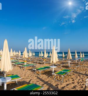 Sunshiny paradise white sandy beach with sunshades and sunbeds (Salento, Puglia, south Italy). The most beautiful sea sandy beach of Apulia. Stock Photo