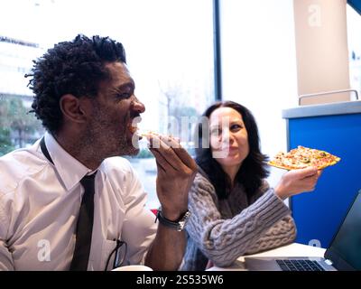 Colleagues Enjoying Pizza During Lunch Break Stock Photo