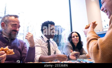Team Laughs Together Over Pizza on a Rainy Day Stock Photo