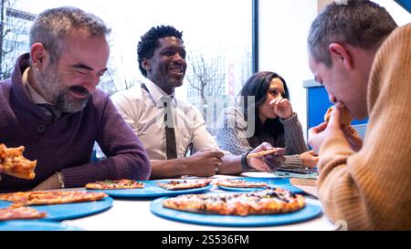 Group of Diverse Colleagues Enjoying Pizza and Laughing Together Stock Photo