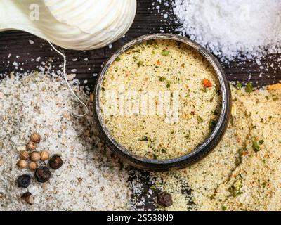 top view of salt cellar and various Seasoned Salts with ingredients close up on dark wooden table Stock Photo