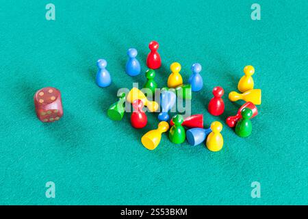 dice and many wooden board game pawns on green baize table Stock Photo