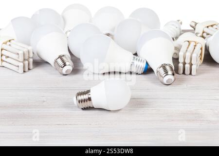 white LED bulb lights and fluorescent tube lamps on gray wooden board and white background Stock Photo