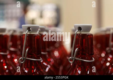 Close-up of the necks of rows of clear red bottles in an industrial setting Stock Photo