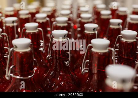 Close-up of the necks of rows of clear red bottles in an industrial setting Stock Photo