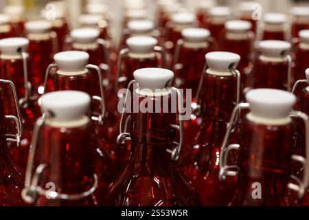 Close-up of the necks of rows of clear red bottles in an industrial setting Stock Photo