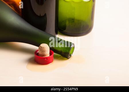 overturned cognac bottle and cork near empty wine bottles on wooden board. overturned bottle and cork near empty wine bottles Stock Photo