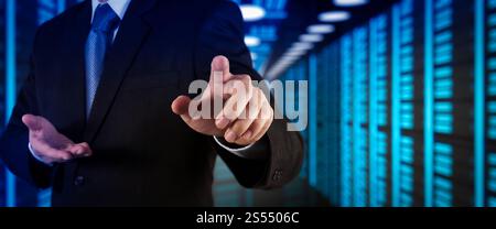 Businessman working with VR wide blank screen computer on server room in background. Stock Photo