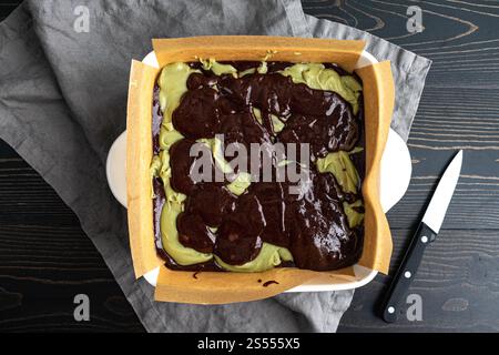 Brownie Batter Layered Over Matcha Cream Cheese Filling: Chocolate brownie batter dolloped onto green tea cheesecake filling in ceramic baking dish Stock Photo