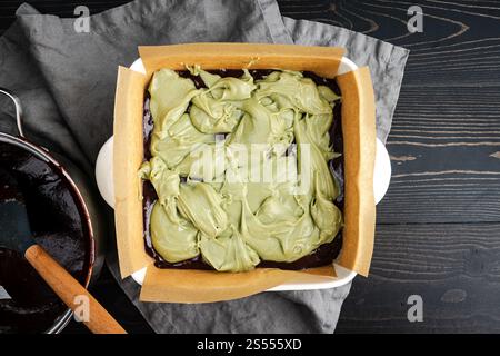 Matcha Cream Cheese Layered Over Brownie Batter: Green tea cheesecake filling dolloped onto brownie batter in a ceramic baking dish Stock Photo