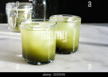 Two Glasses of Matca Soda with Ice Cubes: Sparkling water mixed with matcha simple syrup served in rocks glasses Stock Photo