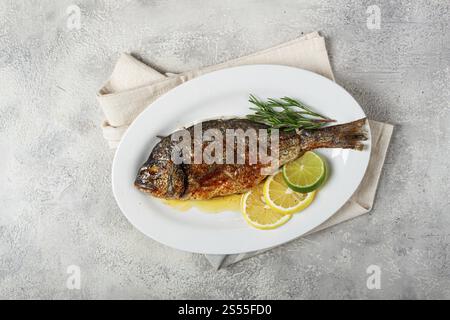 Baked dorado fish, in the oven, fried dorado, with spices and herbs, on a white plate, top view, homemade, no people Stock Photo