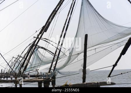 Fort Kochi, Kochi, Kerala, South India, Traditional fishing nets on the seashore with a pale sky in the background, Fort Kochi, Kochi, Kerala, South I Stock Photo