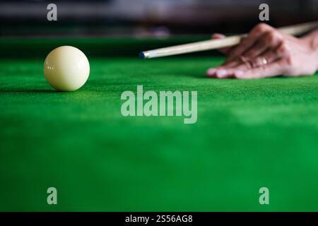 Mans hand and Cue arm playing snooker game or preparing aiming to shoot pool balls on a green billiard table. Colorful snooker balls on green frieze Stock Photo