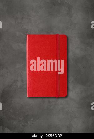 Red closed notebook mockup isolated on dark concrete background. Red closed notebook on dark concrete background Stock Photo