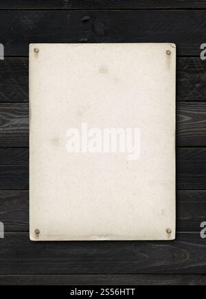 Old textured paper sheet nailed on a black wood table. vertical Mockup. Old textured paper sheet nailed on a black wood table Stock Photo