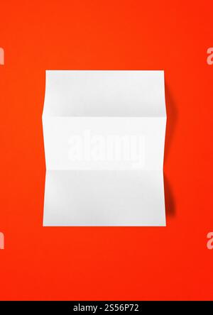 Blank folded White A4 paper sheet mockup template isolated on red background. Blank folded White A4 paper sheet mockup template on red background Stock Photo