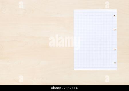 top view of blank sheet of squared paper on light brown wooden board with copyspace Stock Photo