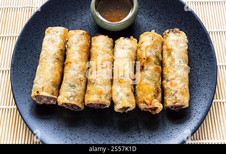 several fried Mon Nem , Vietnamese fried crispy spring rolls close up on black plate Stock Photo