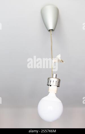ball-shaped LED lamp hangs on wires wrapped in duct tape at home Stock Photo