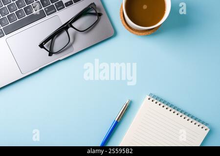 Coffee cup, laptop keyboard and notepad on blue office desk. Business office concept Stock Photo