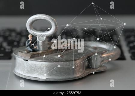 Internet security concept-miniature businessman sit on old key and padlock on laptop computer keyboard Stock Photo