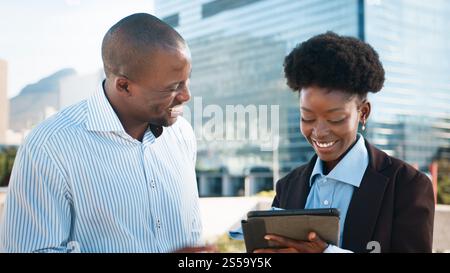 Smiling Professionals Collaborating on a Tablet Outdoors Stock Photo