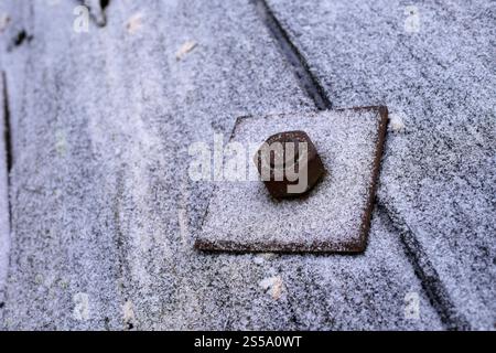 Nut and bolt on a frosty square metal plate on a cable drum. Stock Photo