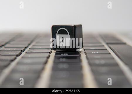 A cube with a padlock symbol on a laptop keyboard. Online security, data protection, and digital privacy concept. Stock Photo