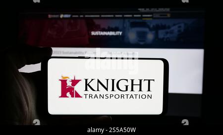 Germany. 17th Oct, 2024. In this photo illustration, a person is holding a cellphone with the logo of Knight-Swift Transportation Holdings Inc. on screen in front of business webpage. Credit: SOPA Images Limited/Alamy Live News Stock Photo