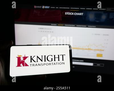 Germany. 17th Oct, 2024. In this photo illustration, a person is holding a mobile phone with the logo of Knight-Swift Transportation Holdings Inc. on screen in front of web page. Credit: SOPA Images Limited/Alamy Live News Stock Photo